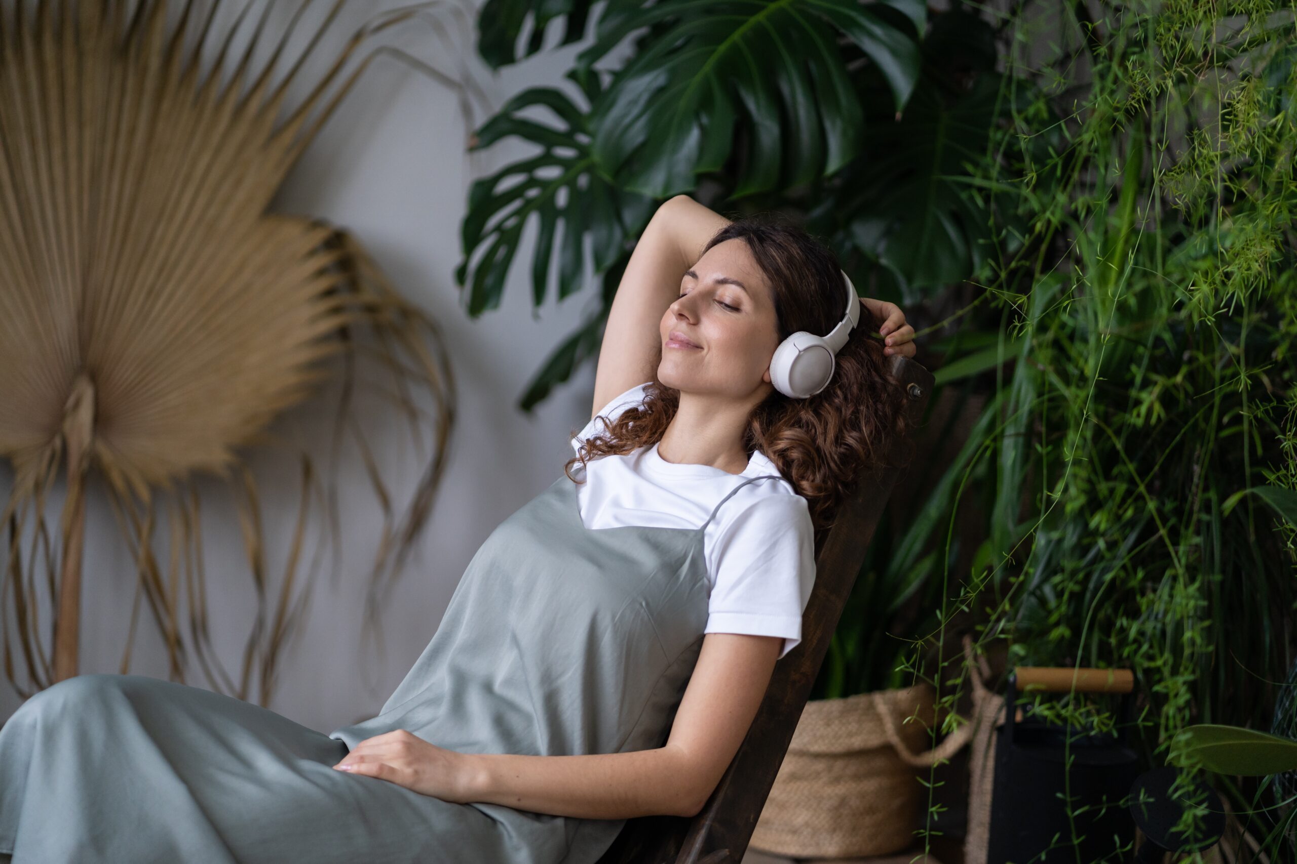 A woman relaxes with headphones on, eyes closed and smiling, illustrating how music influences the brain and body.