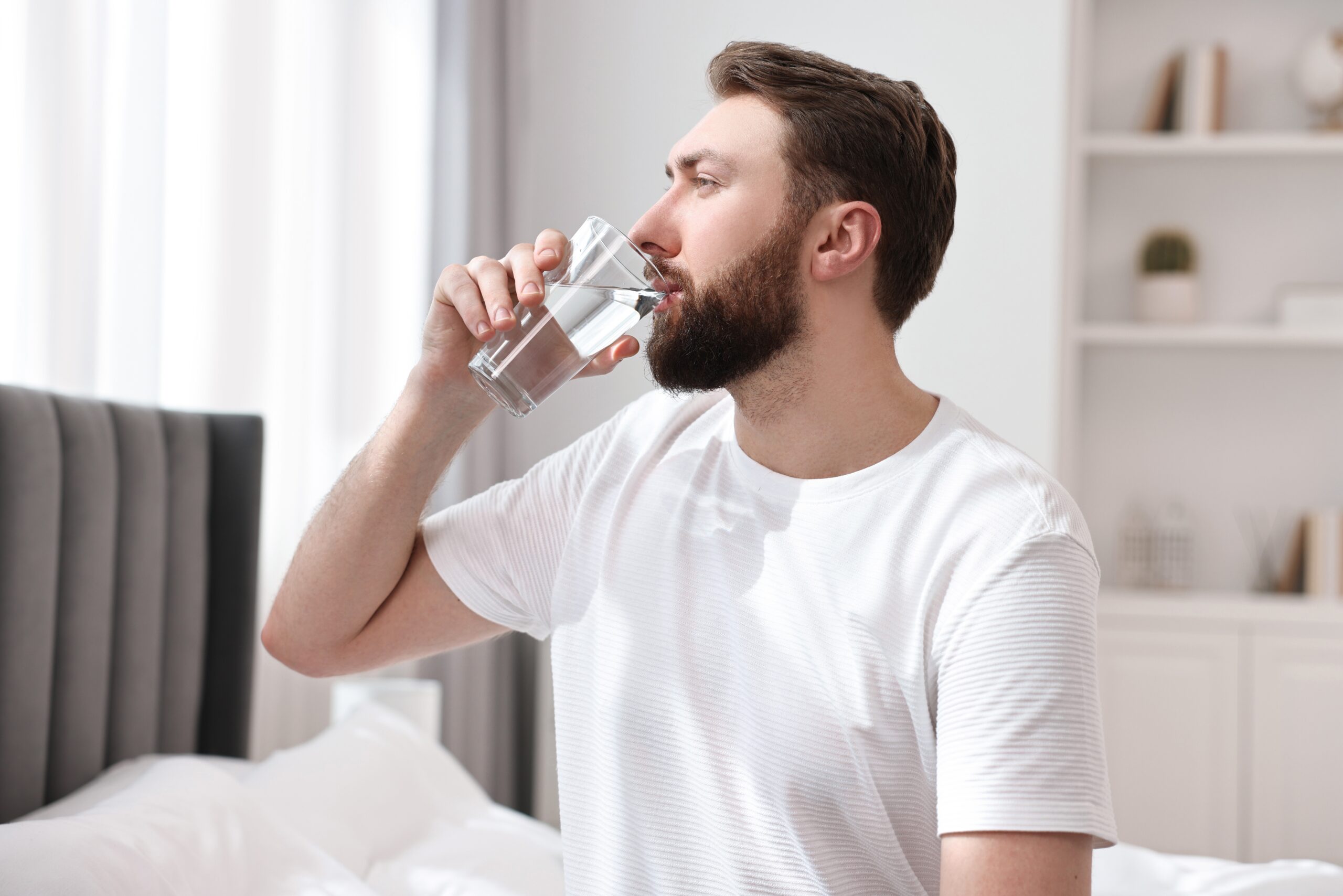 A man drinks a glass of water, emphasizing the importance of staying hydrated.